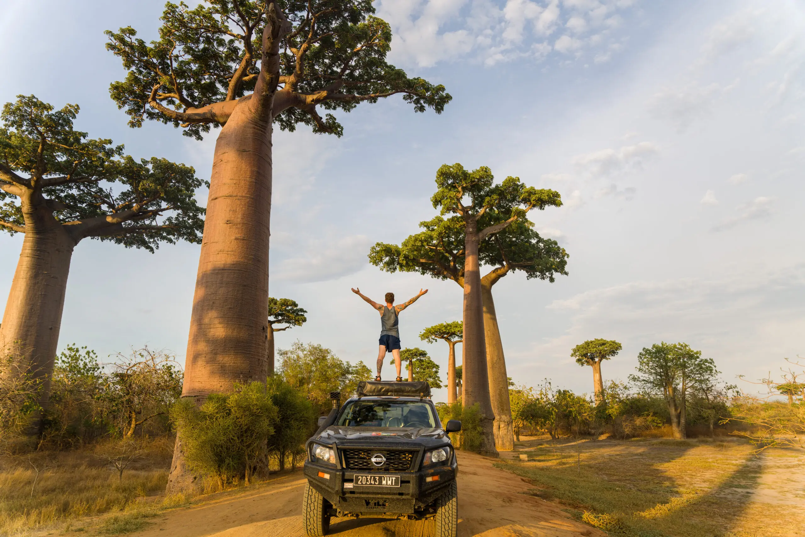 Man standing on a car in Madagascar, during a self-drive trip along the baobabs