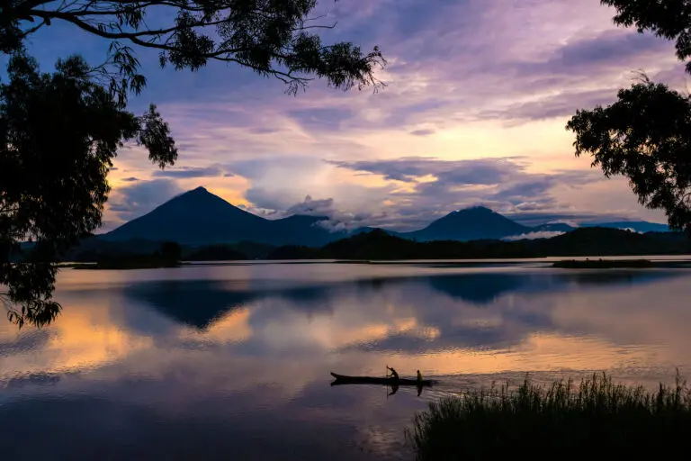 Lake Mutanda view with fishermen in canoe and purple skies during sunset