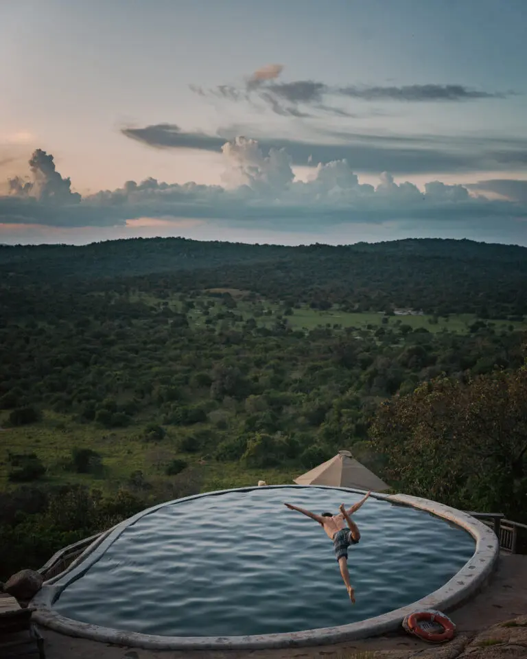 Man diving in infinity pool with savanna in back drop Mihingo Lodge Uganda