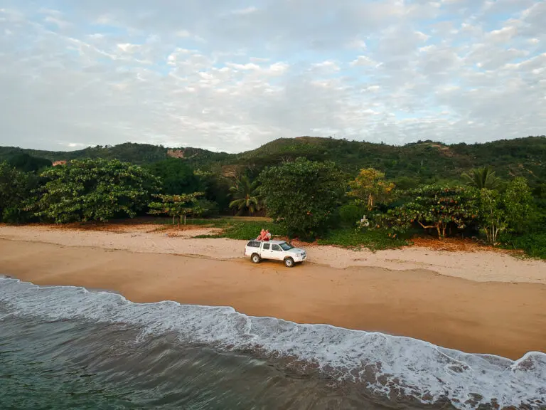 white nissan car on beach waves green back cloudy sky roadtrip madagascar