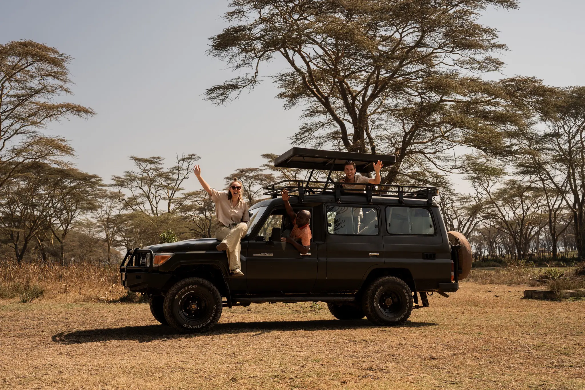 drei fröhliche Menschen in einem Safari-Jeep in Kenya