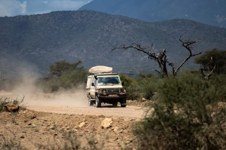 safari vehicle driving on dusty road in Tanzania