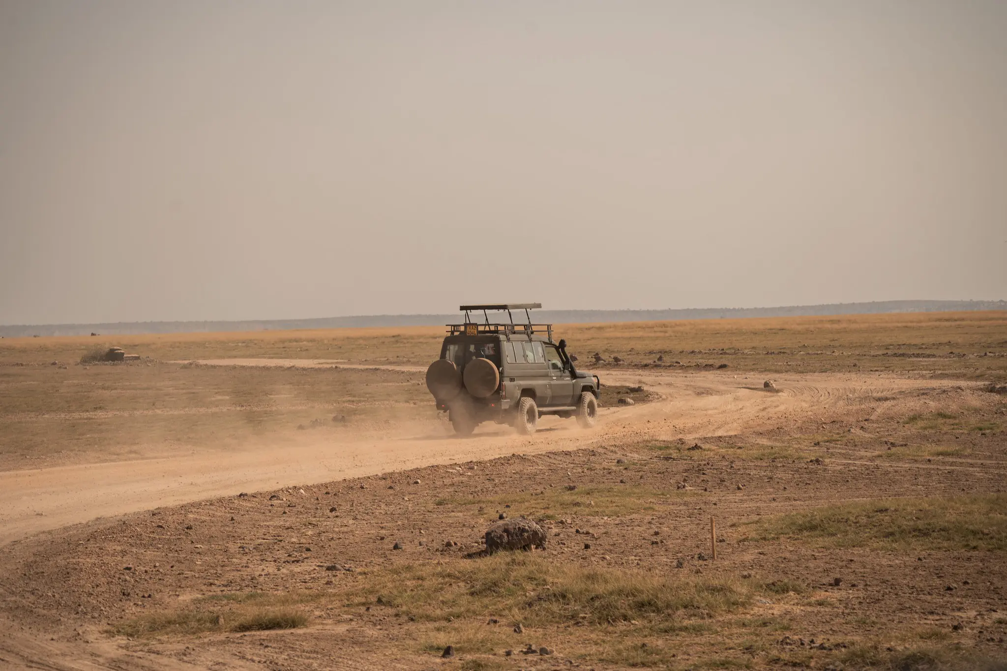 jeep de safari roulant sur une route poussiéreuse au cœur d’une vaste savane