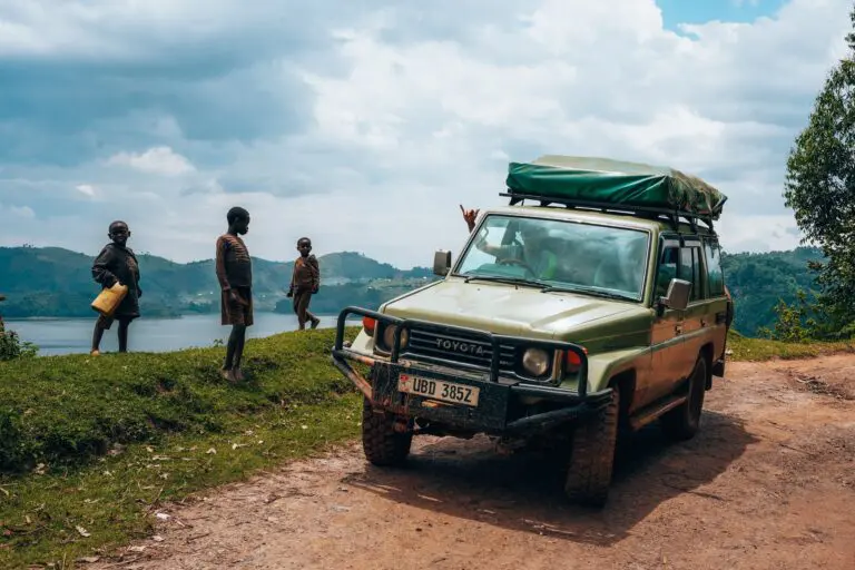 children watching a safari jeep by a lake in Uganda