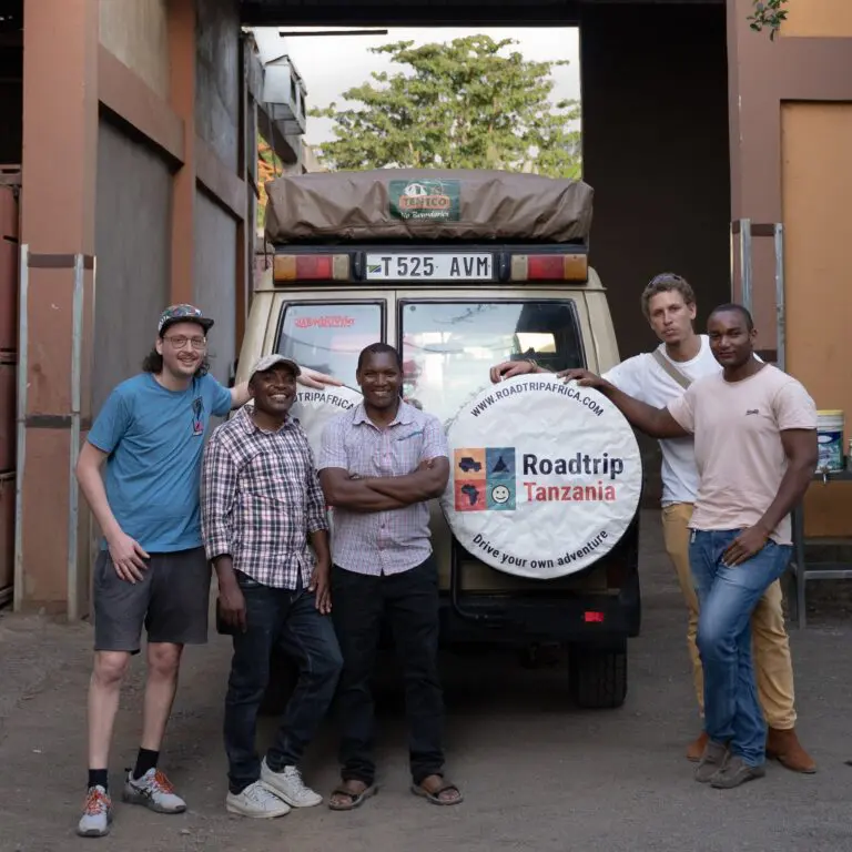group of men posing with Roadtrip Tanzania vehicle