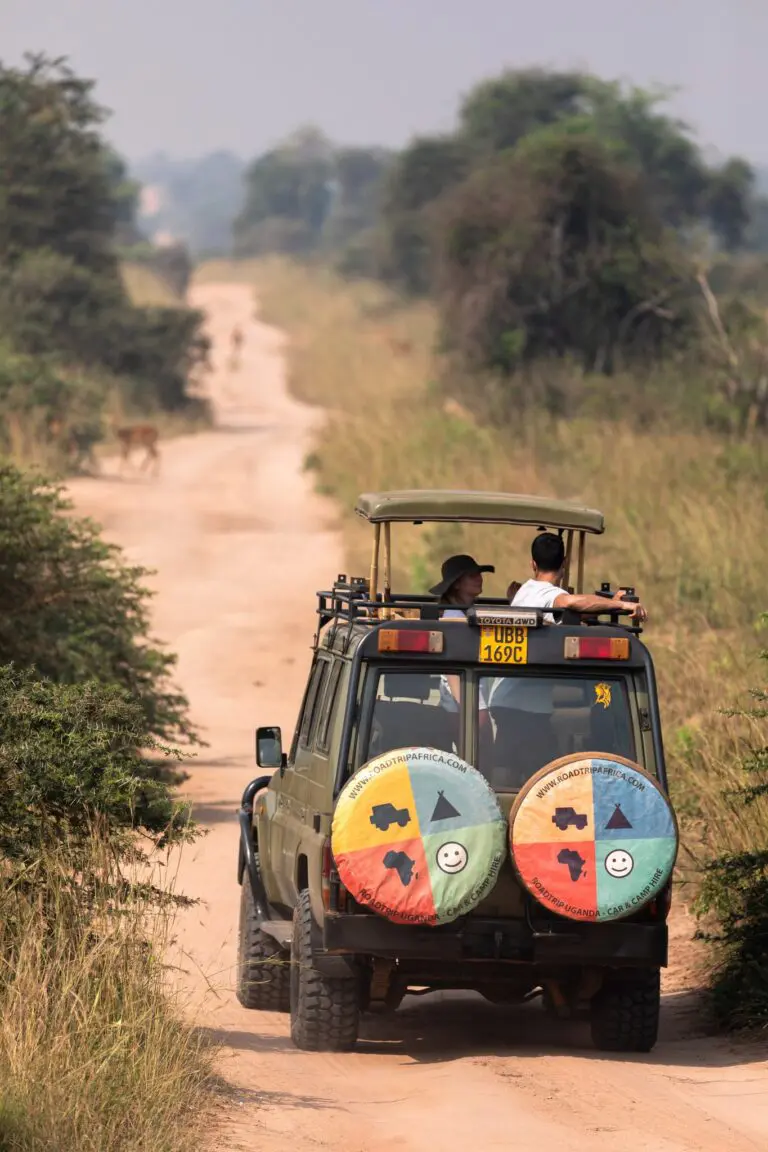 safari jeep with tourists on a dirt road in Uganda